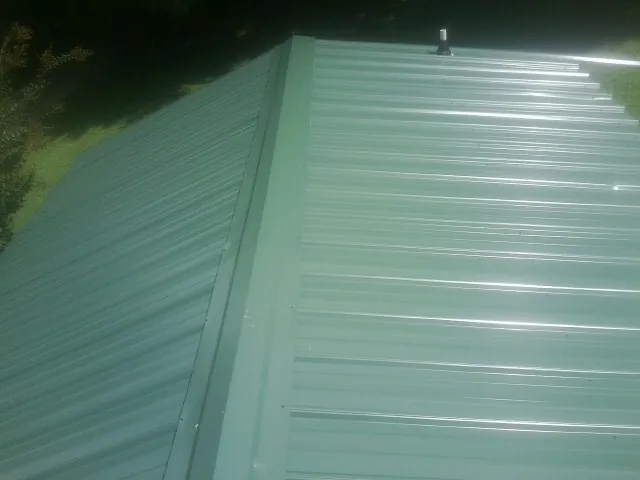 New green metal panels meeting at the ridge of a roof — Flat Roof Repair work by our crew in Robstown