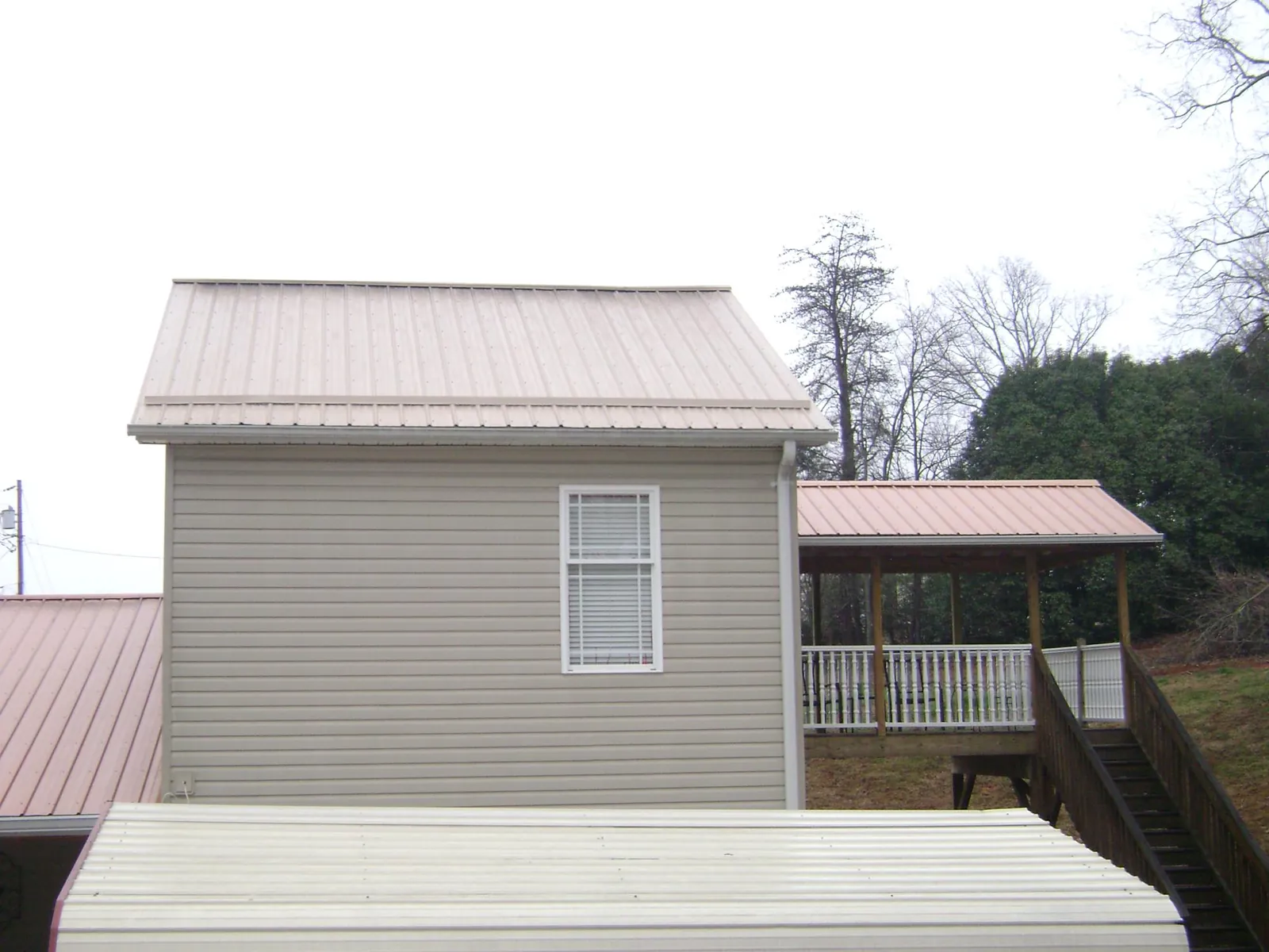 Tan metal roofs on a two story addition and attached porch, from a Roof Replacement job in Robstown