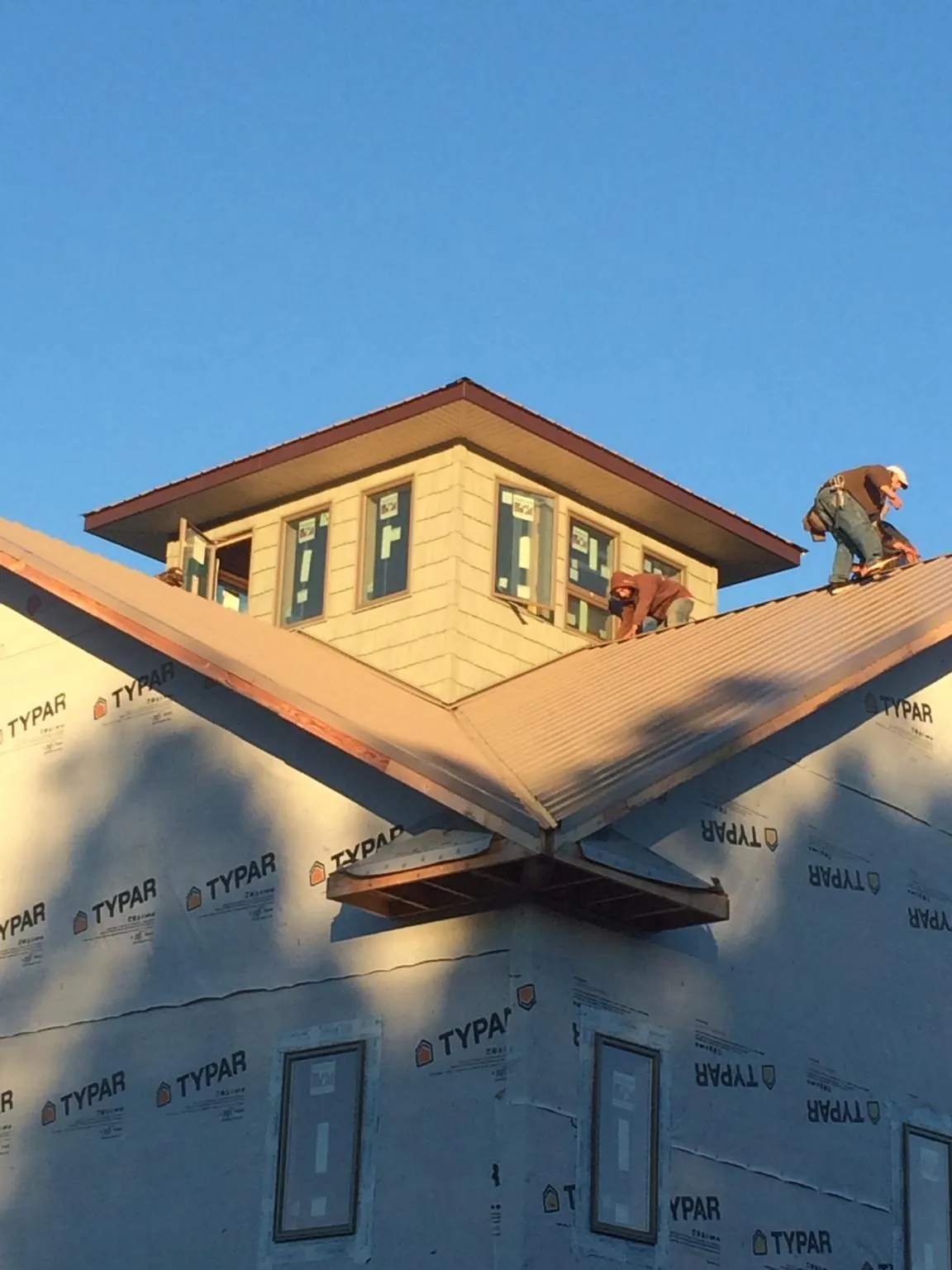 Roofers working around a rooftop cupola on a new metal roof at sunset — Roof Waterproofing in Robstown by Roofing Brothers